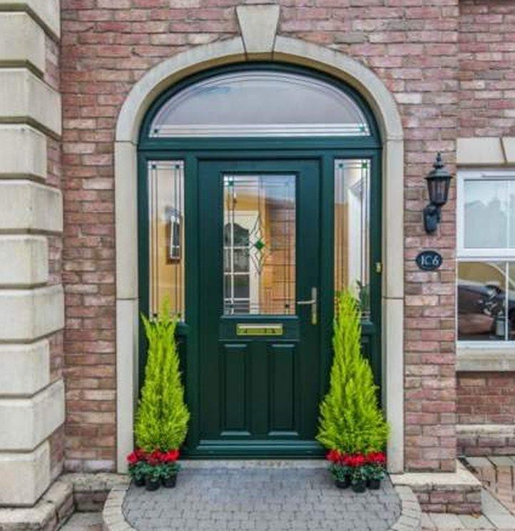 Green composite front door in an arched brick porch